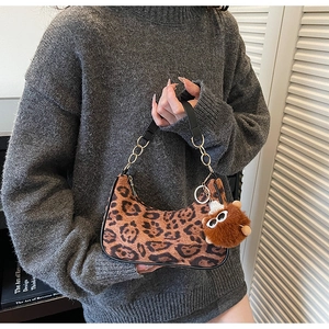 Close-up of leopard print shoulder bag with gold chain strap and plush monster charm