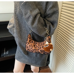 Detail of leopard print underarm bag with gold chain strap and plush charm on grey dress