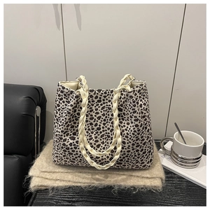 Vista detallada del bolso tote de leopardo con asas de cuerda tejida en superficie texturizada