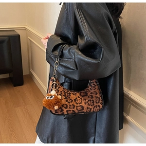 Detail of leopard print crescent bag with plush charm on a black leather jacket