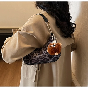 Detail showing vintage leopard print saddle bag with gold chain and plush bear charm