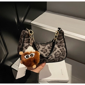 Detail of leopard print suede bag with gold chain and plush keychain accessory