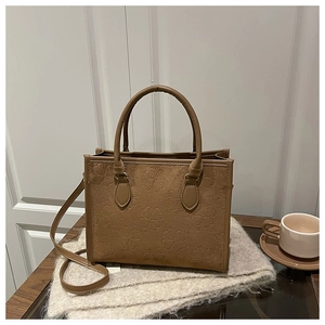 Détails de texture du cabas en daim marron avec motifs trèfles gaufrés sur une écharpe