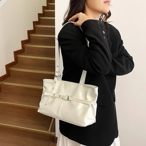 Sac fourre-tout en cuir verni blanc avec boucle argentée porté par un mannequin