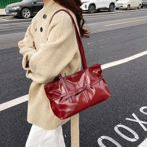 Sac à épaule en cuir verni bordeaux avec boucle décorative et détails métalliques