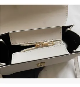 Detailed macro view of the smooth golden zipper and secure magnetic snap on a beige bag