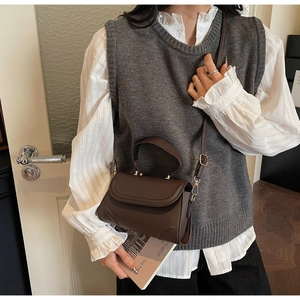 Detail of a dark brown vintage crossbody bag featuring matte leather and gold hardware
