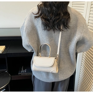 Minimalist cream white mini crossbody bag worn by a model in a modern interior setting