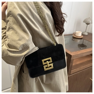 Detail of minimalist black crossbody bag with gold buckle on a stylish trench coat
