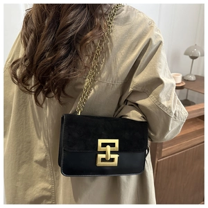 Detail of elegant black chain bag featuring a gold buckle and premium suede leather texture