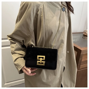 Close-up of black crossbody bag with vintage gold metal clasp on model wearing trench coat