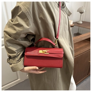 Vue détaillée du sac à main en cuir rouge avec fermoir doré sur un trench-coat