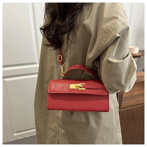 Sac à main rouge en cuir avec fermoir doré porté avec un trench-coat kaki élégant