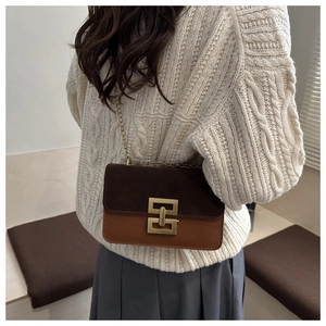 Detail of retro shoulder bag featuring two-tone brown leather and gold chain strap
