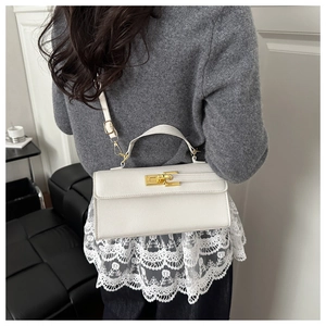 Détail d'un sac à main crème en cuir avec fermoir doré et bandoulière sur le côté