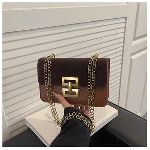 Detail of retro flap bag showing gold geometric metal buckle and mixed material texture