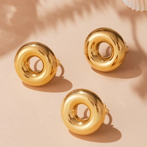 Three hollow chunky gold rings in 18k plated stainless steel on a minimalist beige base