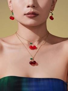 Detail of layered cherry pendant necklaces and matching red resin earrings on model
