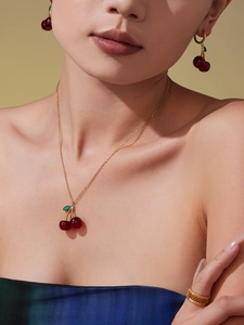 Close-up of a cherry jewelry set with red pendant necklace and gold filigree ring