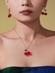 Close-up of a model wearing cute red cherry pendant necklace and matching stud earrings