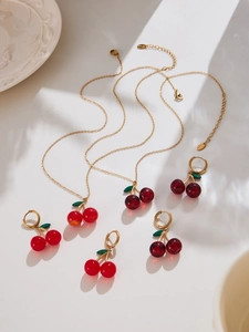 Macro view of cherry pendant necklaces and hoop earrings with green leaf detail