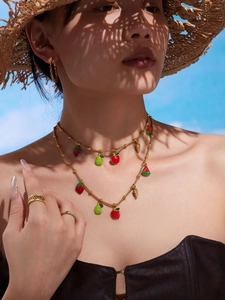 Detail of bohemian gold fruit pendant necklaces with strawberry and avocado charms