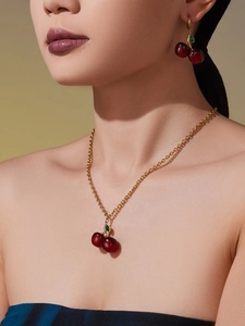 Close-up of red resin cherry pendant necklace and earrings worn by a female model