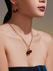 Close-up of model wearing cherry pendant necklace and earrings with red resin details