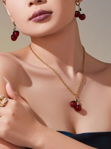 Detailed view of cherry pendant necklace and earrings set on model with resin finish
