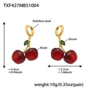 Detail of red resin cherry earrings with green zircon leaves and stainless steel hooks