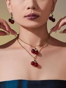 Close-up of a model wearing a double-layer cherry pendant necklace and matching earrings