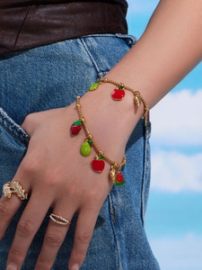 Detail of gold fruit charm bracelet with strawberry, pear and apple enamel pendants