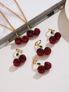 Detail of red resin cherry jewelry set with gold necklaces and matching cherry earrings