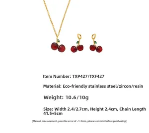 Detail of red resin cherry jewelry set with green zircon leaves and stainless steel chain