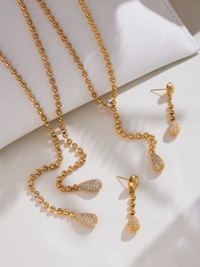 Détail d'une parure en plaqué or 18k avec chaîne à billes et pendentifs en zircon