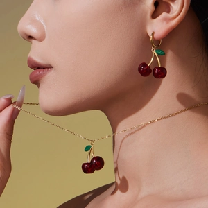 Red cherry resin necklace and earrings set for women with gold tone chain on model