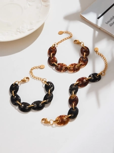 Detailed macro view of resin link bracelets in amber and black with gold connectors
