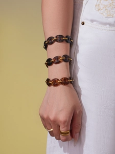 Detailed view of amber resin link bracelets with gold accents on model's wrist