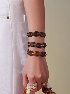 Detail of amber resin link bracelets with 18k gold plating and silk scarf styling