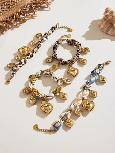 Dettaglio di bracciali in sciarpa di seta con ciondoli a cuore dorati e stampe leopardate