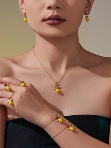 Close-up of elegant lemon pendant earrings and necklace set worn by a fashion model