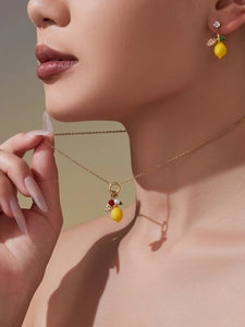 Gros plan sur collier pendentif citron et boucles d'oreilles en zircone et perles sur modèle