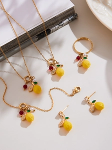 Detailed view of gold lemon jewelry set with yellow zircon pendants on white plate