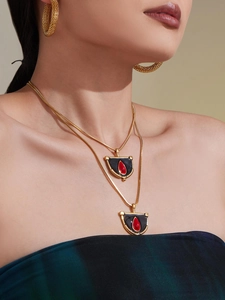 Détail du collier double chaîne serpent dorée avec pendentif en émail noir et pierre rouge
