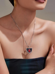 Détail du pendentif bouclier avec pierre rouge et émail noir sur chaîne serpent argentée