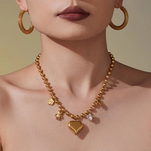 Collier à billes dorées avec pendentifs cœurs et créoles texturées sur un modèle