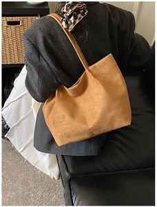 Brown suede tote bag shown on shoulder featuring minimalist design and spacious interior