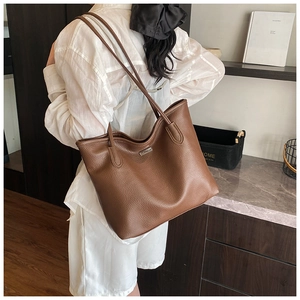 Détail du sac cabas marron en cuir grainé avec plaque métallique et fines bandoulières