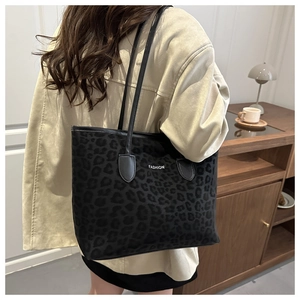 Detailweergave van zwarte tote bag met luipaardprint en Fashion-tekst op een model