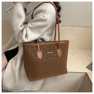 Detail of leopard print tote bag with white FASHION lettering and thin brown straps